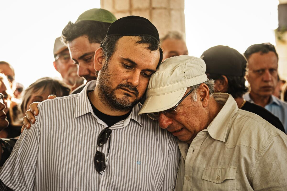 YEHUD, ISRAEL -- 15 DE OCTUBRE DE 2023: Miembros de la familia consuelan a Jimmy Levy mientras lamentan el fallecimiento de su hermano Daniel Levy, quien fue asesinado en el Kibbutz BeOeri en un asalto sin precedentes de Hamás contra comunidades cercanas a Gaza, durante el funeral de DanielOs en Yehud Cementerio en Yehud, Israel, domingo 15 de octubre de 2023. No digo esto en voz alta, pero necesito preguntarle a Dios por qué N ¿por qué fue asesinado este buen hombre? O dijo Michael Levy, cuyo hermano Daniel, de 34 años, Un anciano médico nacido en Perú y padre de dos hijos, fue asesinado en su kibutz en las afueras de Gaza mientras intentaba atender a los heridos a su alrededor.  En todo Israel y dentro de la Franja de Gaza, la magnitud de la muerte en este conflicto está abrumando a los vivos.  Instituciones desde hospitales hasta morgues.  Desde los laboratorios forenses hasta los cementerios se tambalean bajo el peso.  Al menos 1.400 personas han muerto en Israel y unas 2.800 en Gaza desde el 7 de octubre, cuando comenzó la guerra actual con un ataque transfronterizo del grupo militante Hamás.  (MARCUS YAM/LOS ANGELES TIMES)