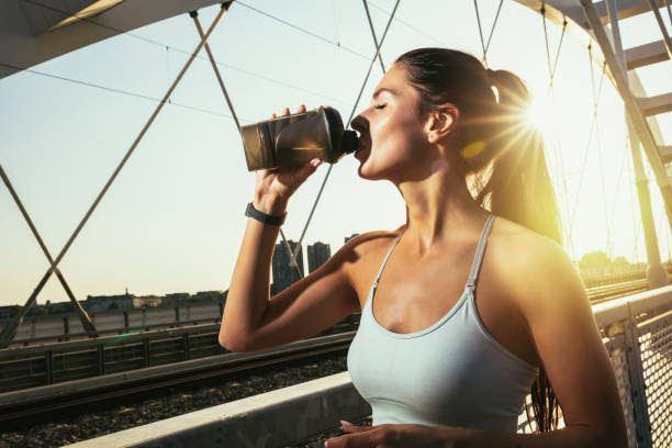 Fitness woman drinking water from bottle. Muscular young female taking a break from workout outside. Fitness woman drinking water from bottle. Muscular young female taking a break from workout outside. slim fit ladies stock pictures, royalty-free photos & images