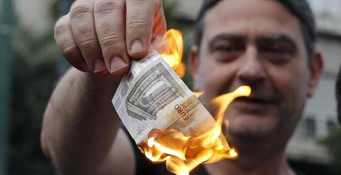 Dos personas queman unos billetes de euro en una manifestación anti austeridad frente a las oficinas de la Comisión Europea en Bruselas. REUTERS/Alkis Konstantinidis
