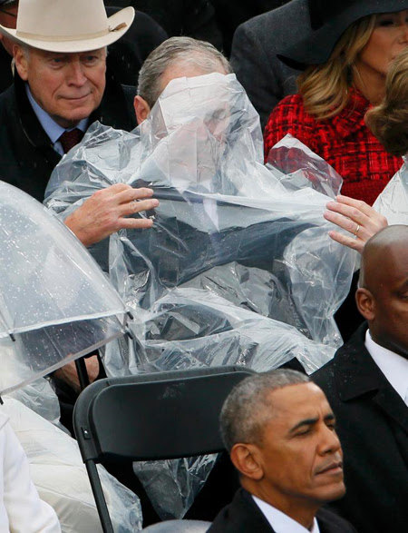 Chiếc áo mưa bị thổi che cả mặt vị cựu tổng thống.
