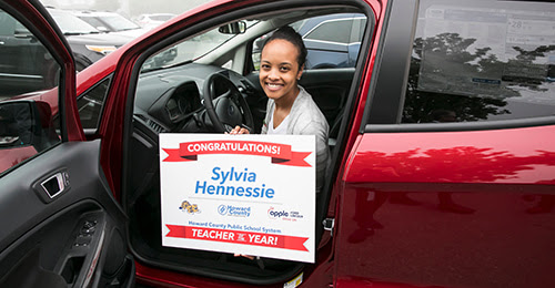HCPSS Teacher of the Year Sylvia Hennessie sitting in her new car.