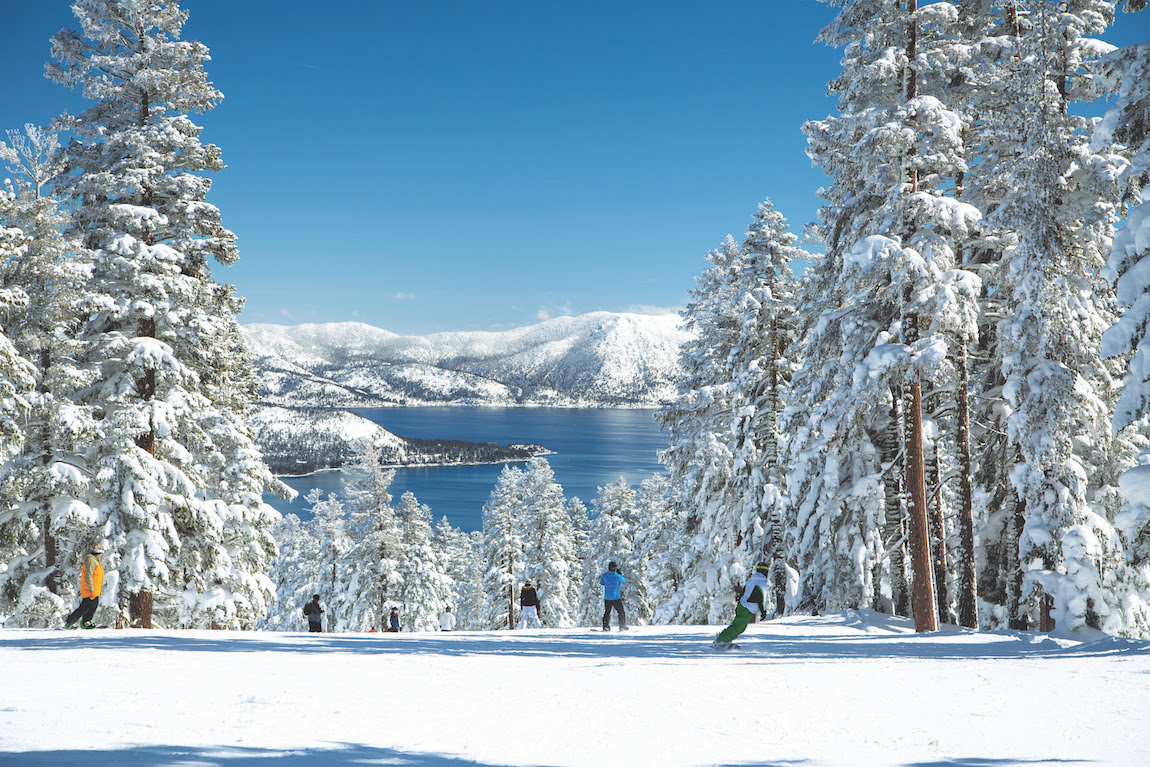 Skiers in slope on top of beautiful mountain with lake view