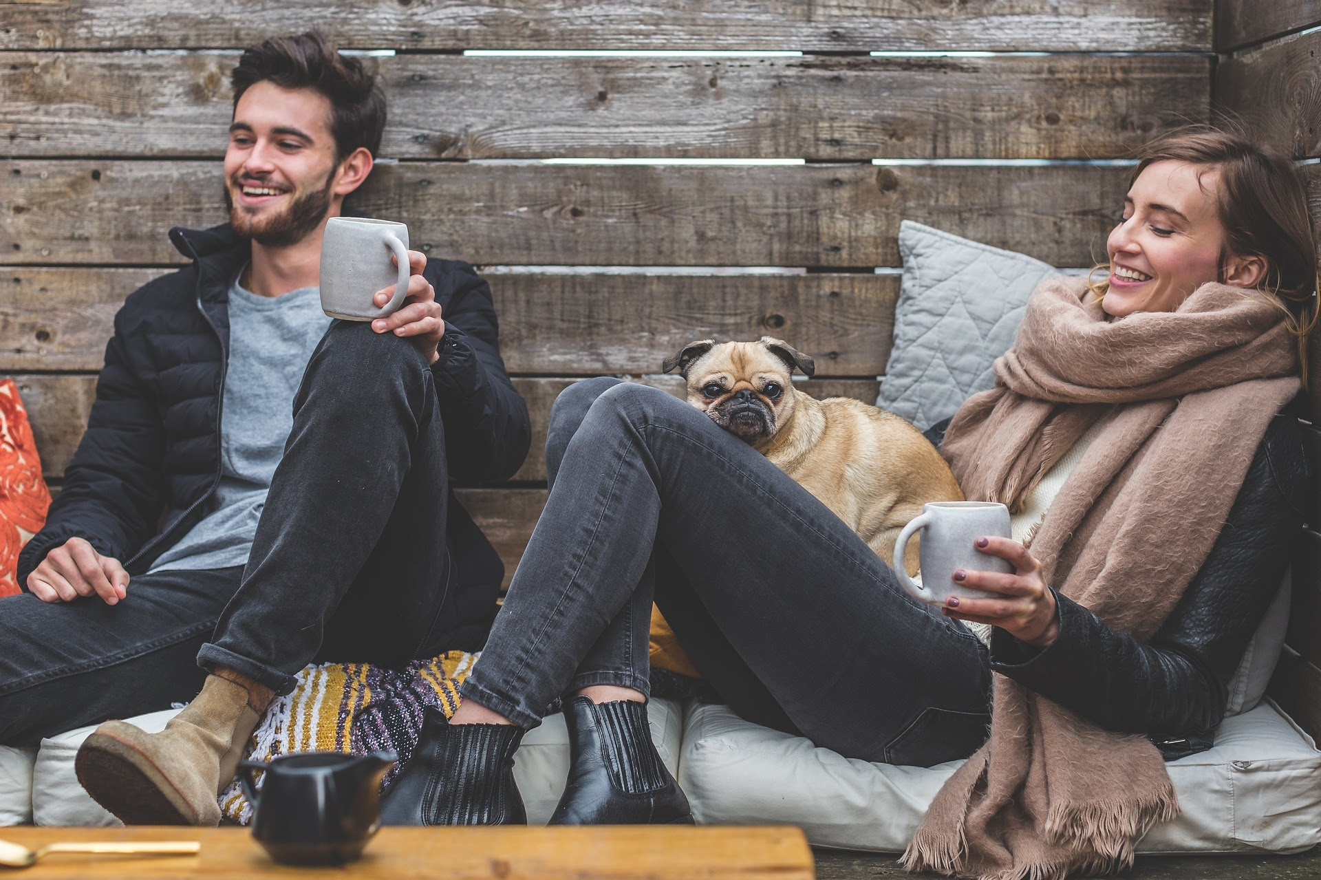 Image os a man and woman talking and drinking coffee with a dog