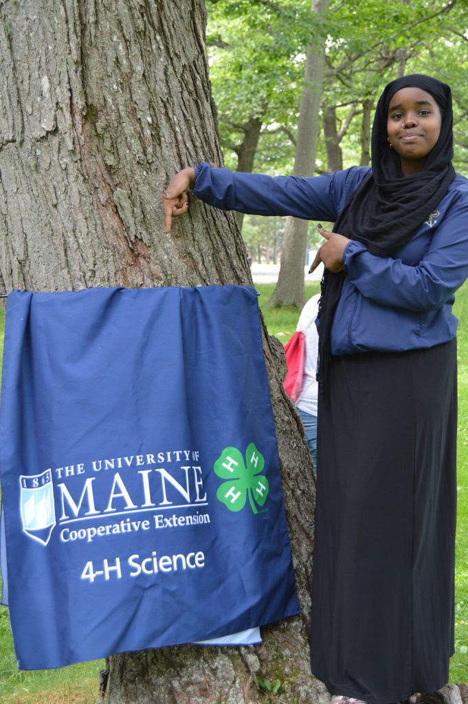 teen at 4H summer of science with a banner from the event