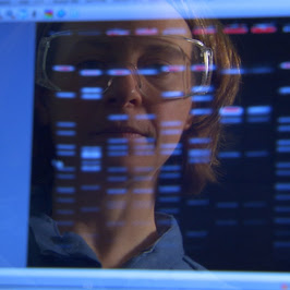 Photograph: Scientist's image is reflected on computer screen.
