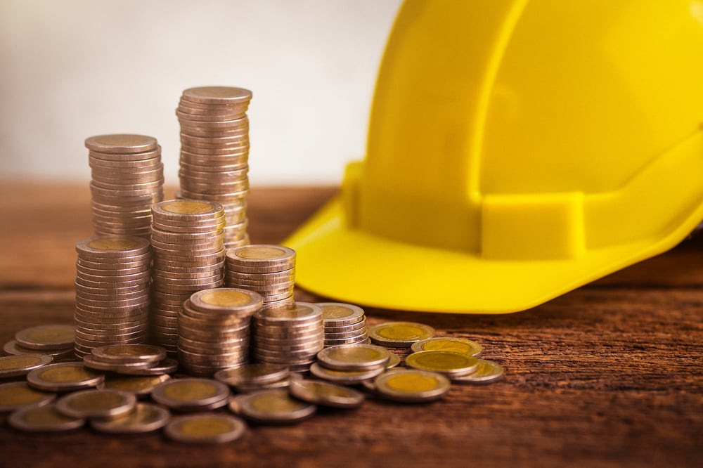 A hardhat behind a stacks of euros A hardhat behind a stacks of euros