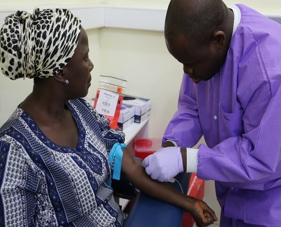 investigator collects a blood sample from genomic study participant