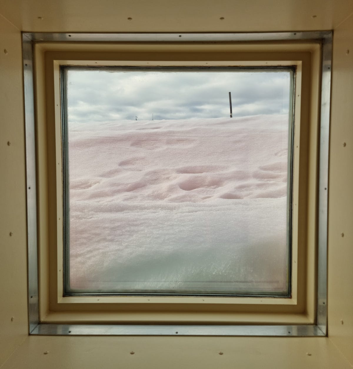 Looking through a window into a buildup of snow, which obscures the view