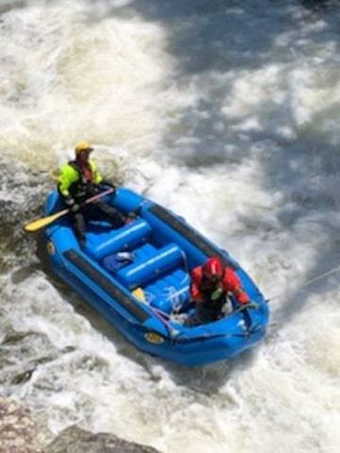overhead view of a raft with Forest Rangers on board in an area of rushing water