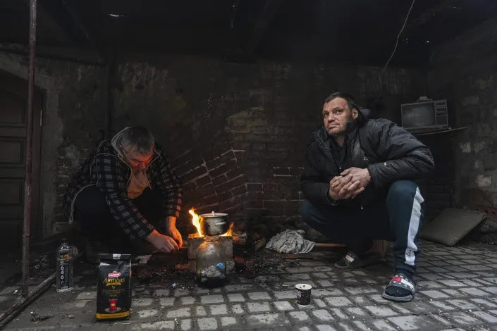 Men cook a meal outside over an open flame in Mariupol.