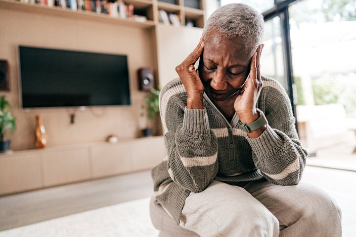 Older woman feeling severe headache pain. She has both hands on her temples rubbing her head in pain.