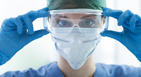 doctor wearing googles, mask, gown, and gloves
