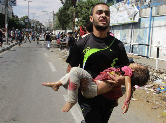 A Palestinian man carries a child killed in a blast outside a UN run school in Rafah, in the southern Gaza Strip, Sunday, Aug. 3, 2014. UNRWA's Director of O...