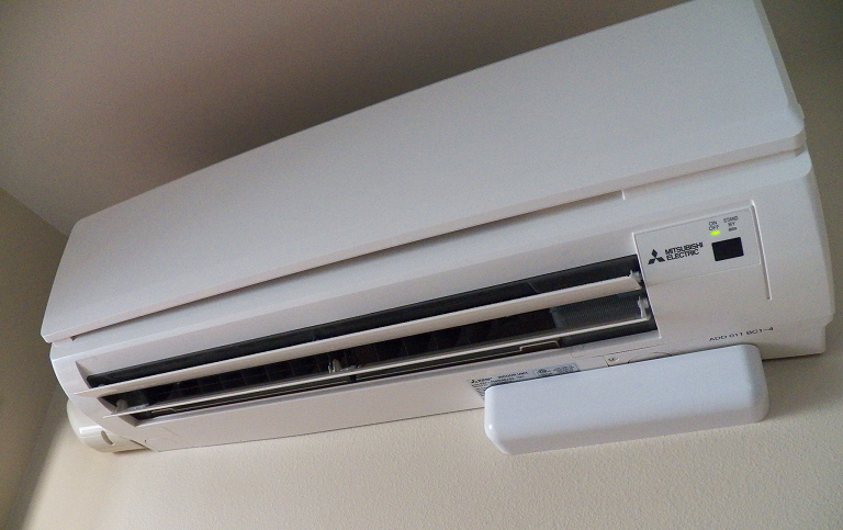 A photo of a large white heat pump installed on the wall of a home.