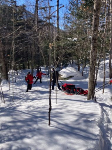 Rangers pull injured hiker on sled through snowy woods