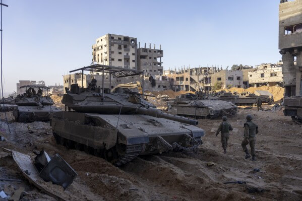 FILE - Israeli army troops are seen next to a destroyed building during a ground operation in the Gaza Strip on Nov. 8, 2023. As the military sets its sights on southern Gaza in its campaign to stamp out Hamas, key challenges loom. International patience for a protracted invasion has begun to wear thin. And with some 2 million displaced Gaza residents staying in crowded shelters in the south in dire conditions, a broad military offensive there could unleash a new humanitarian disaster during the cold, wet winter. (AP Photo/Ohad Zwigenberg, File)