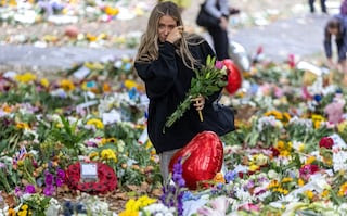 A member of the public wipes away a tear as she lays flowers in Green Park, London