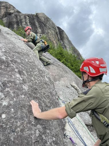 Rangers climbing steep rockface