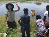 Park Ranger standing in water in front of class and waving at the camera