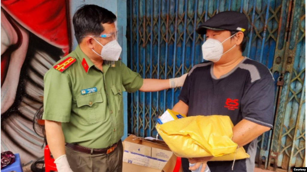 Ông Đinh Văn Nơi (trái) tặng quà cho người dân. (Hình: CTV via Thanhnien.vn)