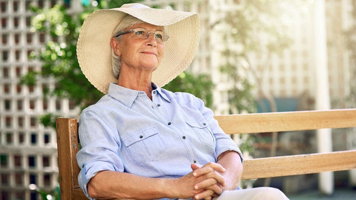 Senior woman relaxing wearing a sun hat in the garden