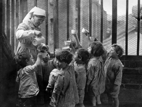 Một nữ y tá rót sữa cho những đứa trẻ tại một nhà trẻ ở Whitechapel, Anh