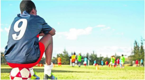 niño sentado en una pelota en una prueba de fútbol niño sentado en una pelota en una prueba de fútbol