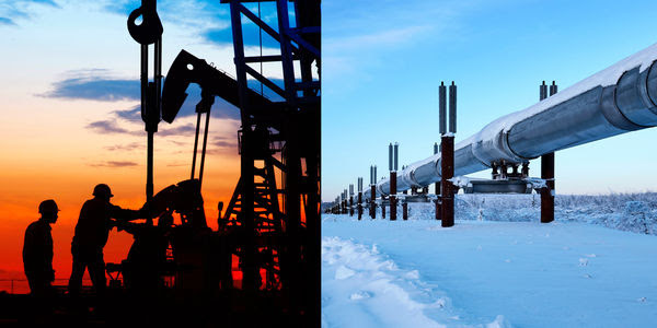 A crew of workers stand on the site of an oil drill, next to a pipeline in the snow.
