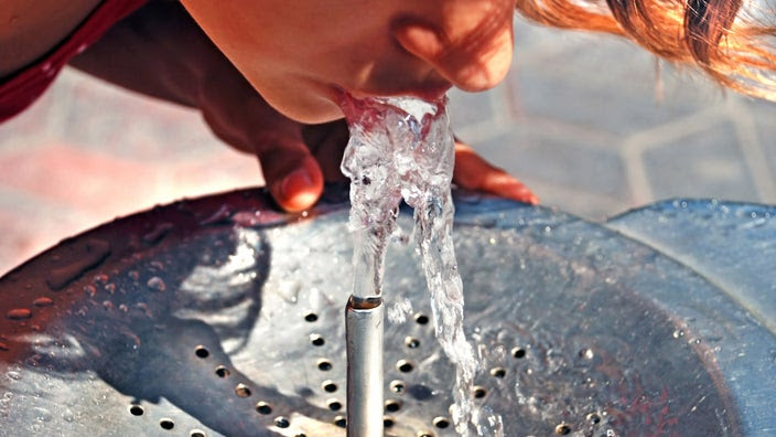 A cropped shot of someone drinking from a water fountain.