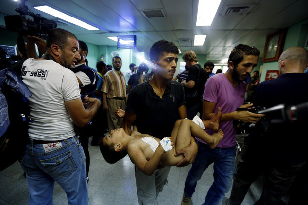 A Palestinian man carries a child, wounded in an Israeli strike on a compound housing a U.N. school in Beit Hanoun, in the northern Gaza Strip, towards the e...