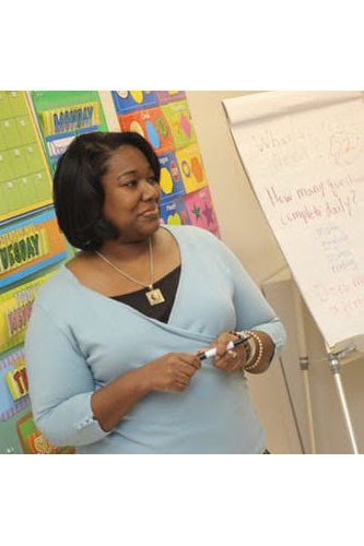 Image of teacher standing in front of a flipchart with a marker in hand. Image of teacher standing in front of a flipchart with a marker in hand.