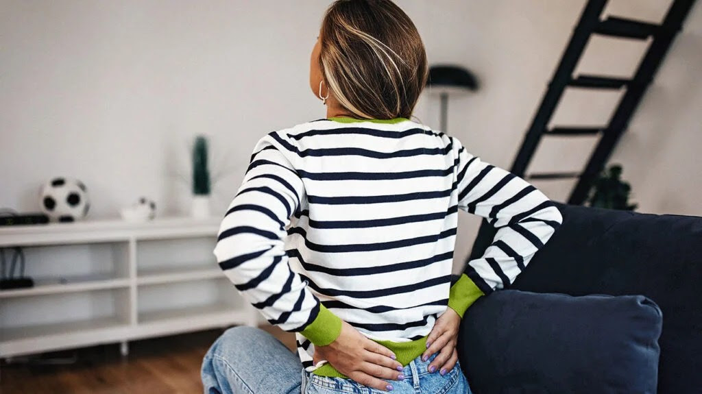 Female sitting down with her hands on her lower back