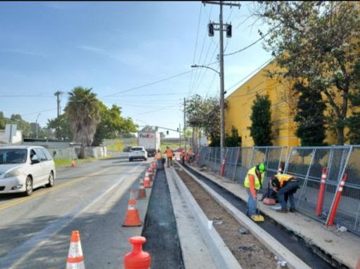 Crews place asphalt for slot paving on Iris Avenue.