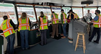 Several people in the pilothouse of a ferry