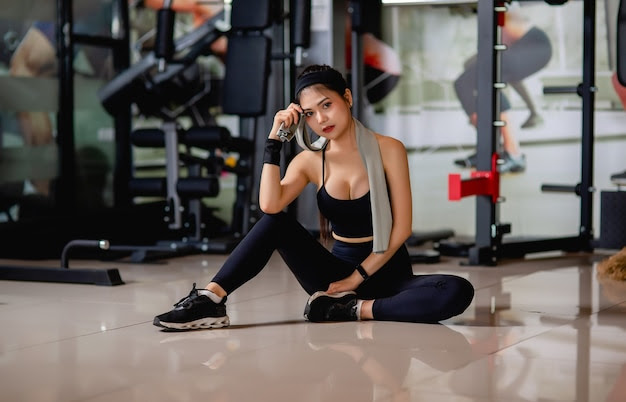 portrait-young-sexy-woman-wearing-sportswear-smartwatch-sitting-floor-wipe-sweat-after-workout-gym-1