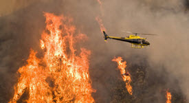 helicopter flying over burning forest
