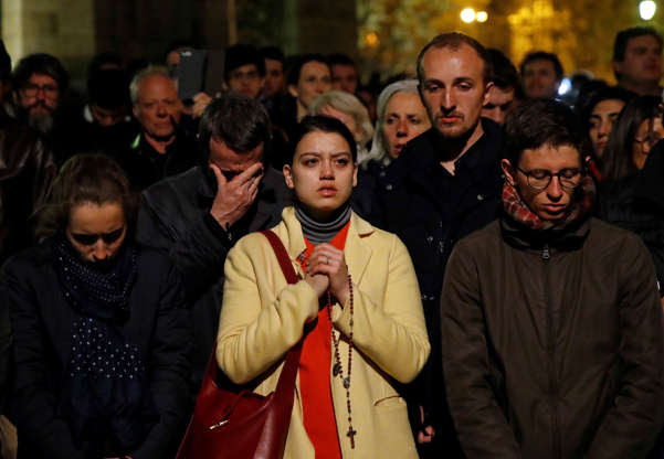 Slide 11 of 31: People pray as Notre Dame cathedral burns in Paris, Monday, April 15, 2019. Massive plumes of yellow brown smoke is filling the air above Notre Dame Cathedral and ash is falling on tourists and others around the island that marks the center of Paris. (AP Photo/Christophe Ena)