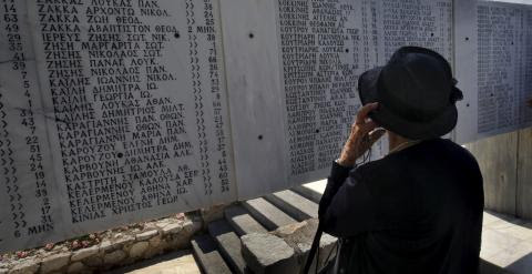 Una persona contempla la placa conmemorativa de las víctimas que las tropas nazis causaron en el pueblo de Distomo al noroeste de Atenas. - REUTERS