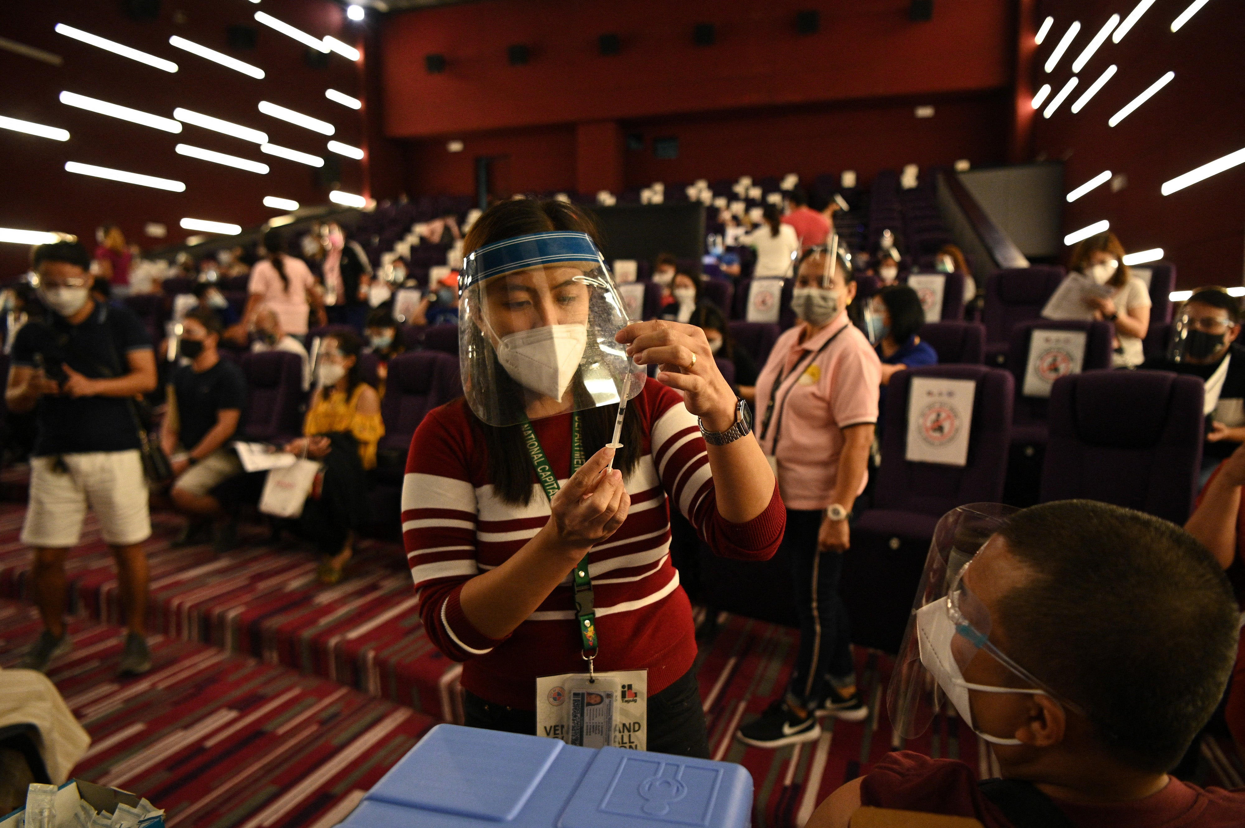 A health worker prepares a vial of Chinese Sinovac vaccine against Covid-19 coronavirus disease inside a movie theatre turned into a vaccination centre in Taguig City suburban Manila on June 14, 2021.