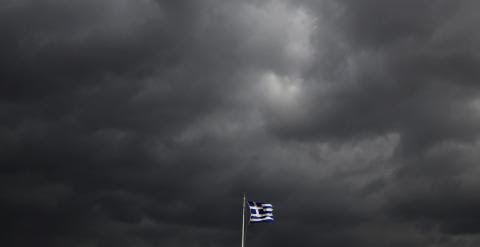 La bandera griega ondea sobre la Acrópolis de Atenas, bajo un cielo cubierto de nubes de tormenta. REUTERS/Yannis Behrakis