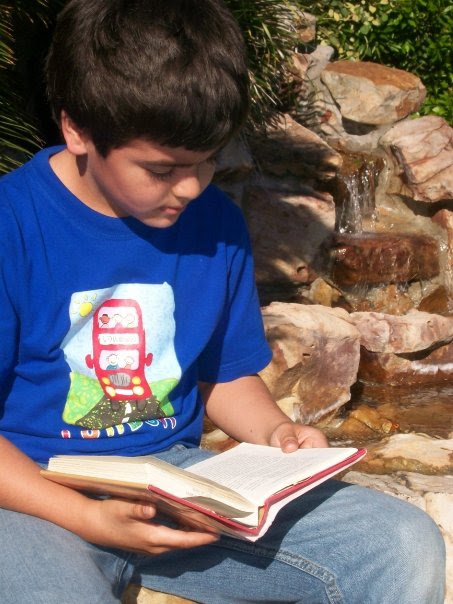 Antonio reading a book by the brook.