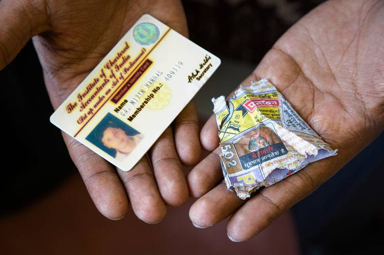 Analyst Nitin Mangal displays his accountant’s ID and the wrapper for Indian cigarettes that he says were used as currency in jail.