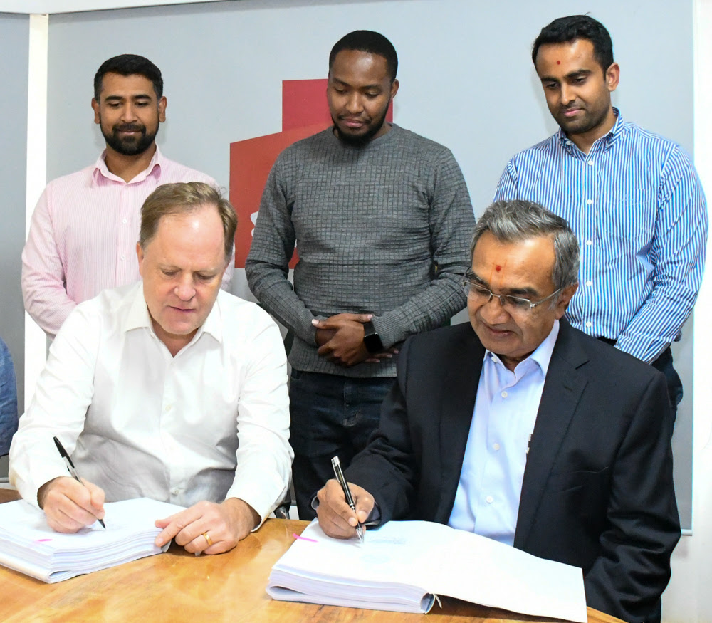 (L-R) Preston Mendenhall, Country Head, Kenya, at Rendeavour, the owner and developer of Tatu City, and Manji Kanji Raghwani, Managing Director, Laxmanbhai Construction, sign the contract. Looking on: Amit Joshi, Senior Project Manager, Tatu City, James Marumi, Legal Counsel, Tatu City, and Khusal Raghwani, Project Manager Laxmanbhai.-Newsline.co.ke