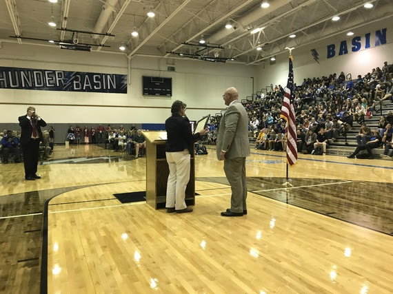 Campbell County School District Superintendent #1, Dr. Boyd Brown, stands at the podium in Thunder Basin High School gym full of students, staff, and community members while a staff member reads the Governor's proclamation.