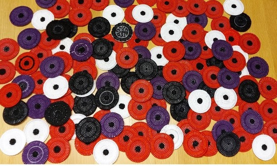 Colour phot showing a pile of stitched poppies in white, red, black and purple.