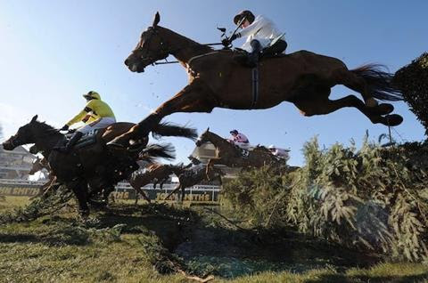 A shot from below of horses jumping at the Grand National, Aintree.