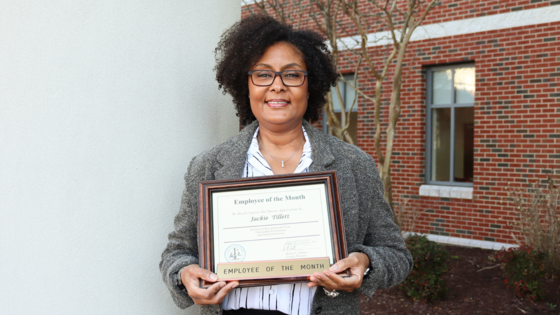 Image of Jackie Tillett holding her framed Employee of the Month certificate.