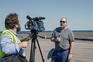 Chris Korleski is interviewed by WLUC-TV6 Houghton Bureau reporter Jake Swope on the stamp sands.