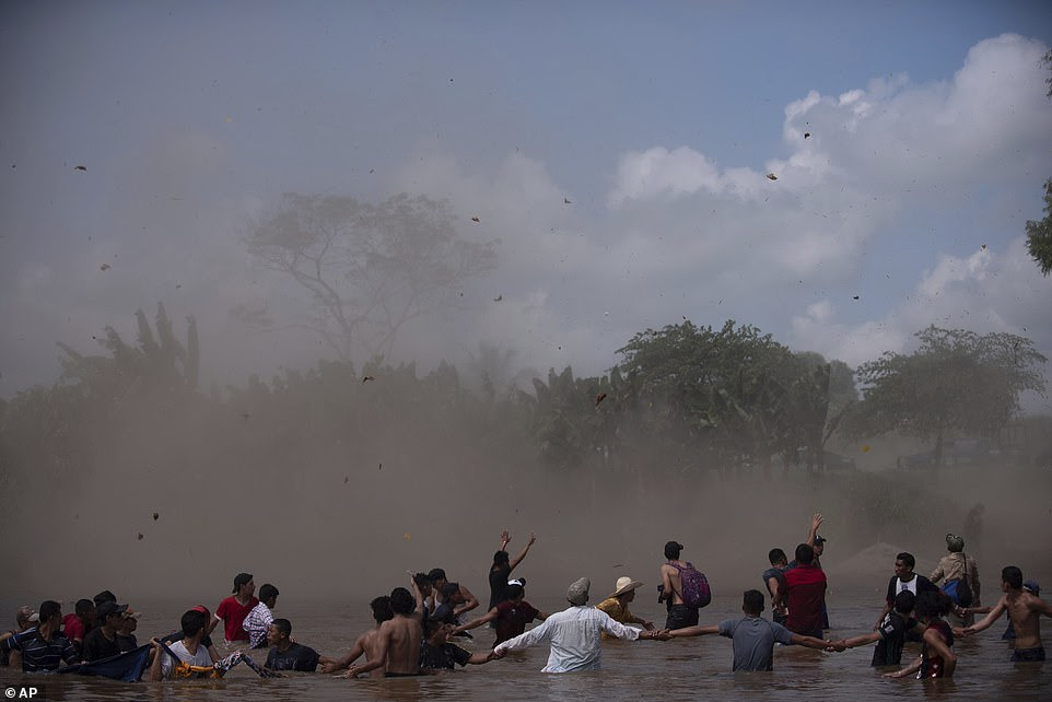Dust clouds are created by a Mexican Federal Police helicopter flying close to the Suchiate River  in order to create a downwash force to discourage the migrants bound for the US border