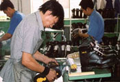 Chinese factory workers produce boots on a factory floor